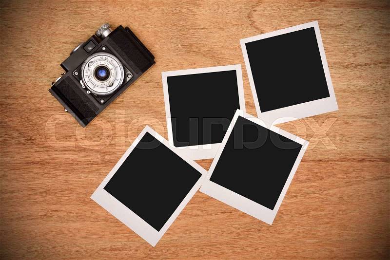 Vintage camera with four blank photo card on wooden table, stock photo