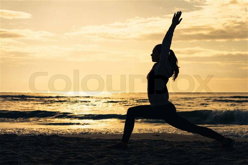 Silhouette of a woman on the beach during morning exercises at sunrise, stock photo