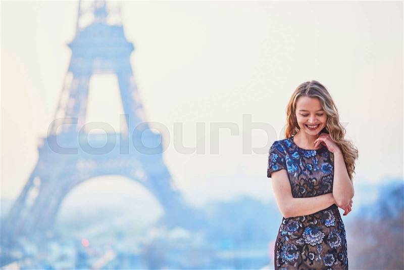 Beautiful elegant Parisian woman near the Eiffel tower at early morning, stock photo