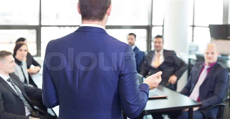 Successful team leader and business owner leading informal in-house business meeting. Businessman working on laptop in foreground. Business and entrepreneurship concept, stock photo