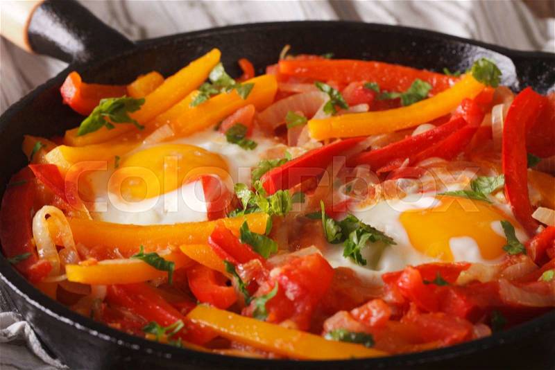Piperrada: peppers with fried eggs on the frying pan macro. horizontal , stock photo