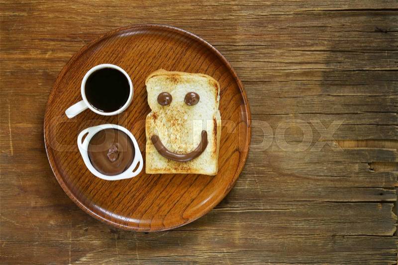 Breakfast serving funny face on the plate (toast, chocolate spread and coffee), stock photo
