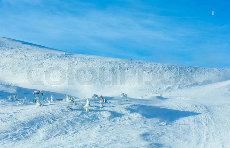 Ski lift on winter morning hill and moon in blue sky, stock photo