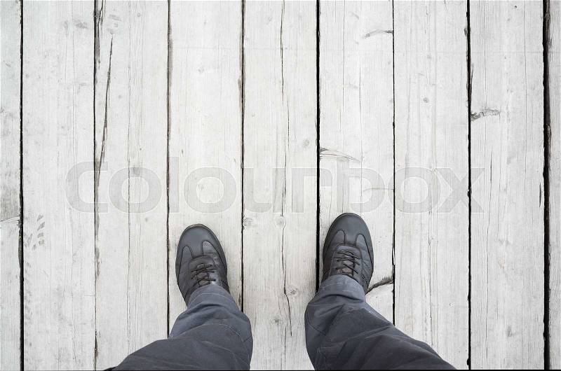 Male feet in leather shoes stand on white wooden floor, first person view, stock photo