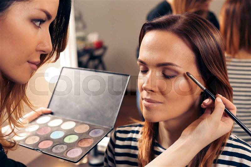 Make up eye shadow in beauty saolon with palette of colors and professional brush near the mirror, stock photo