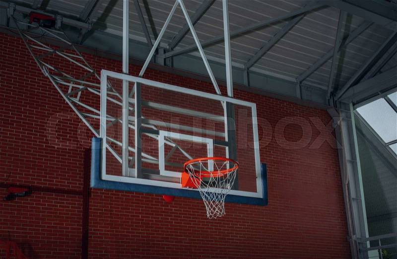 Basketball equipment on an indoor court with a view from below of the hoop, net and backboard on the goalpost, stock photo