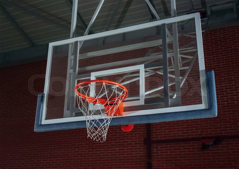 Basketball equipment on an indoor court with a view from below of the hoop, net and backboard on the goalpost, stock photo