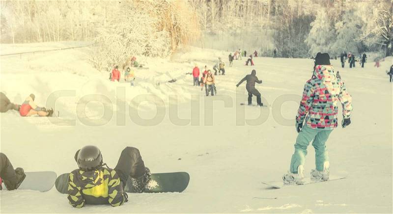 People on snowboards watching snowboarders on background, stock photo