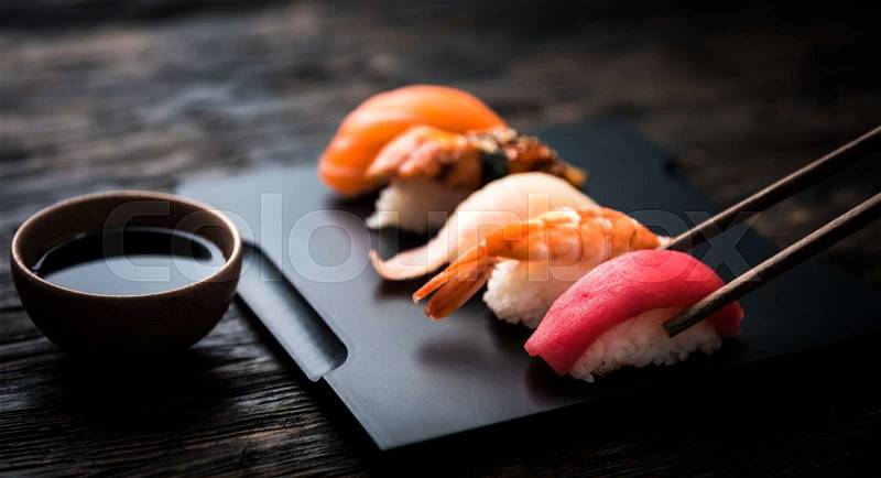 Close up of sashimi sushi set with chopsticks and soy on black background, stock photo