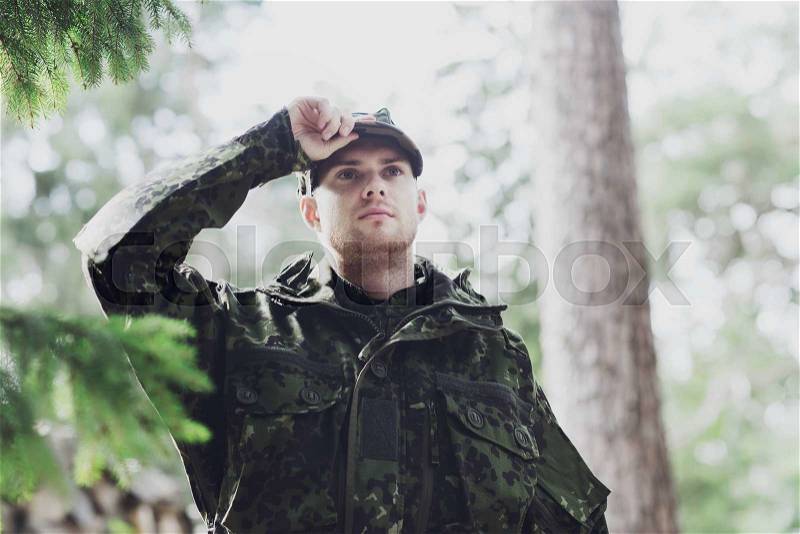 War, army and people concept - young soldier or ranger wearing military uniform in forest, stock photo