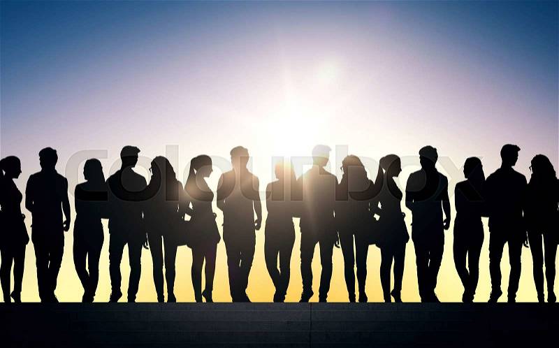 Friendship, education and people concept - silhouettes of friends or students on stairs over sun, stock photo