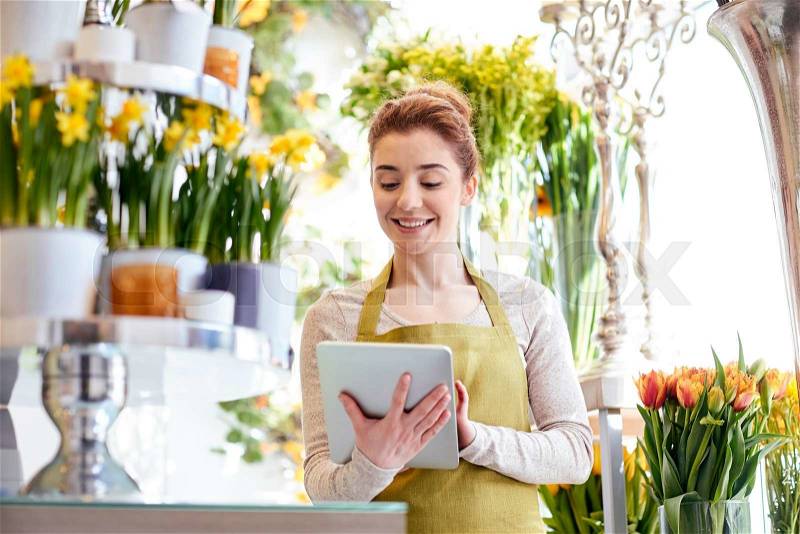 People, business, technology, sale and floristry and concept - happy smiling florist woman with tablet pc computer at flower shop, stock photo