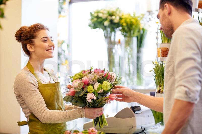 People, shopping, sale, floristry and consumerism concept - happy smiling florist woman making bouquet for and man or customer at flower shop, stock photo