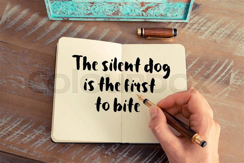 Handwritten quote The silent dog is the first to bite as inspirational concept image, stock photo