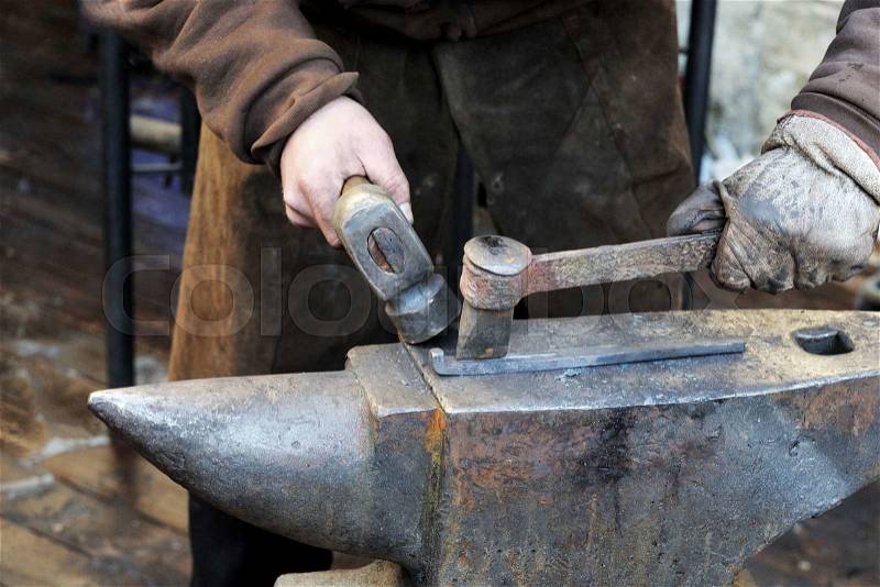 Blacksmith forges a horseshoe in a smithy, stock photo