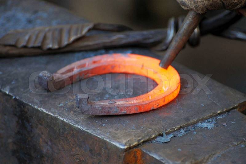 Blacksmith forges a horseshoe in a smithy, stock photo