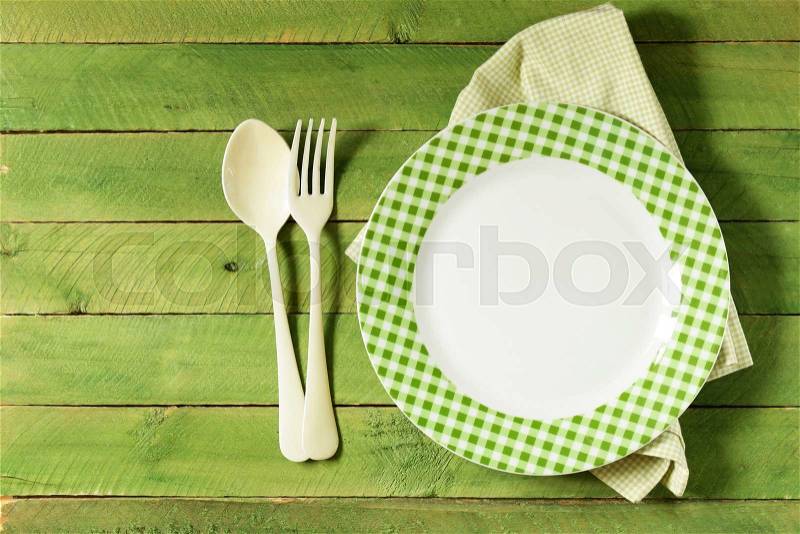 Empty plate with cutlery and napkin on wooden background, stock photo