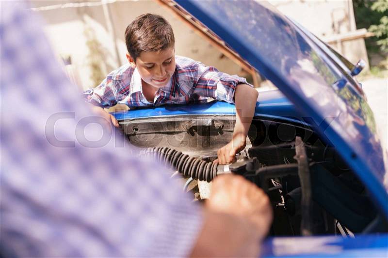 Family and Generation gap. Old grandpa spending time with his grandson. The senior man teaches to the preteen child to fix the engine of a vintage car from the 60s. They smile happy, stock photo