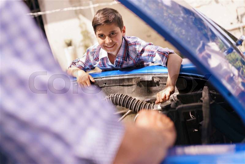 Family and Generation gap. Old grandpa spending time with his grandson. The senior man teaches to the preteen child to fix the engine of a vintage car from the 60s. They smile happy, stock photo