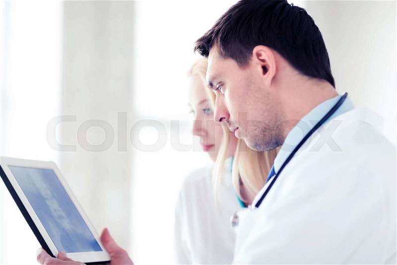 Healthcare and medical - two doctors looking at x-ray on tablet pc, stock photo