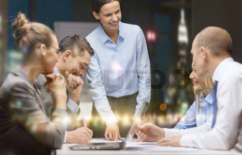 Business, technology and office concept - smiling female boss talking to business team, stock photo