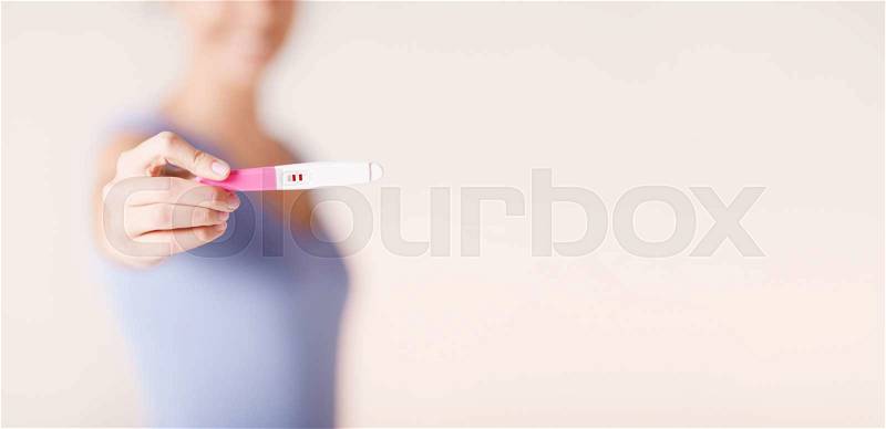 Health care concept - close up of happy woman holding and showing pregnancy test, stock photo