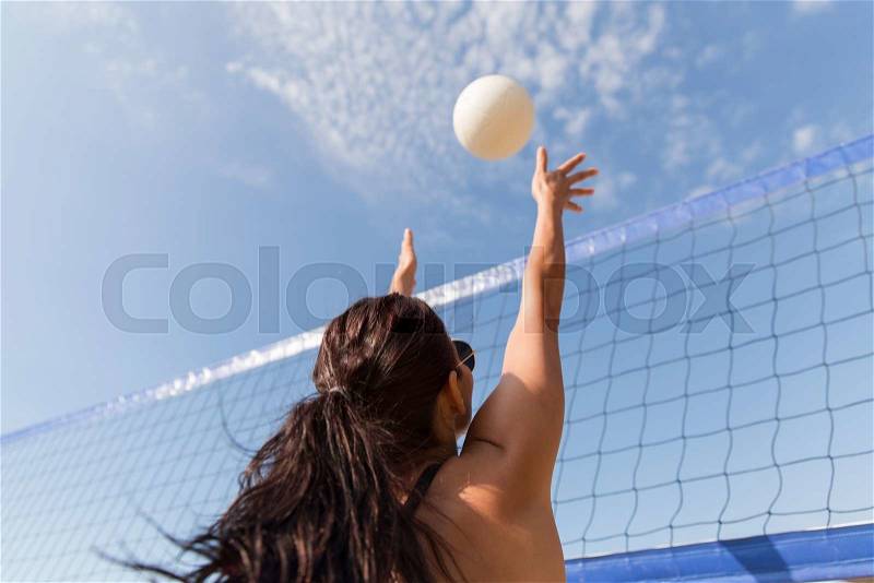 Summer vacation, sport, leisure and people concept - young woman playing volleyball on beach and catching ball, stock photo