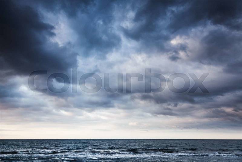 Dramatic stormy dark cloudy sky over sea, natural photo background, stock photo