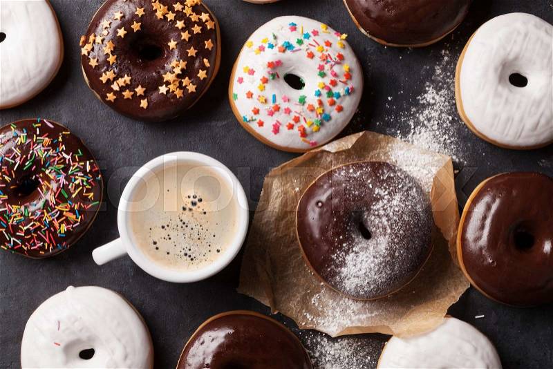 Colorful donuts and coffee on stone table. Top view, stock photo