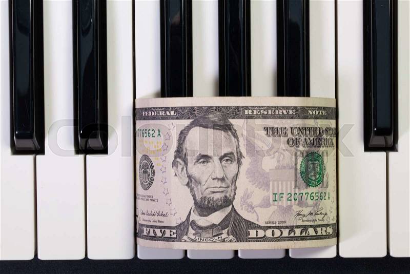 Detail of piano keyboard and US dollar banknote, stock photo
