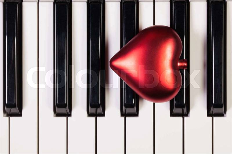 Detail of piano keyboard and red heart, stock photo