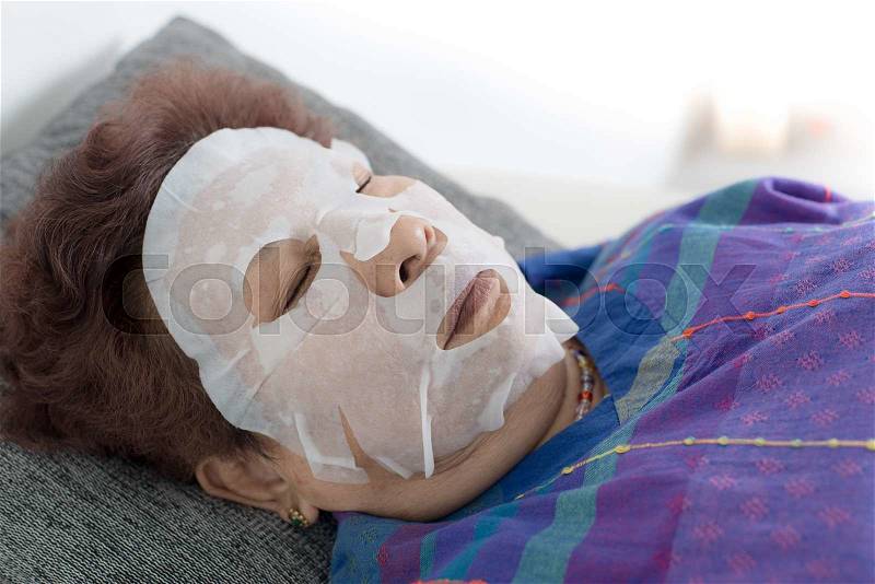 Senior woman using facial mask beauty treatment at home, stock photo