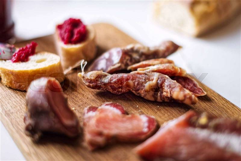Top view horizontal image of various meats on serving board with ham, pork, beef and homemade bread with beetroot-horseradish spread on rustic wood. Selective focus, stock photo