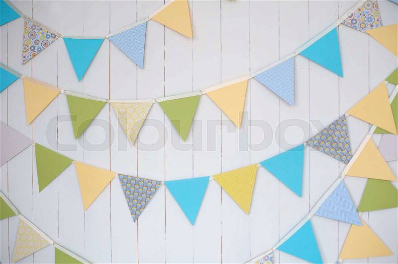 Birthday decoration flags on a plain white wall shot with tilt and shift, stock photo