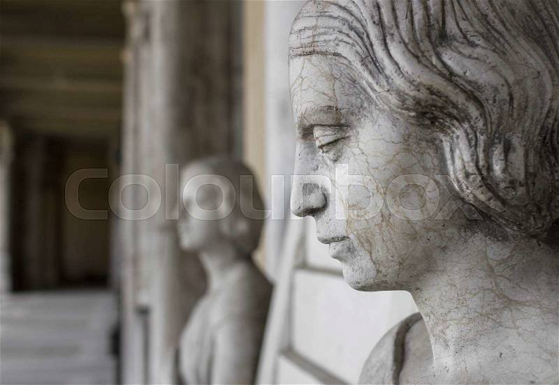 Profile of young sad woman, In the background another statue of a woman and the hall of the museum, stock photo