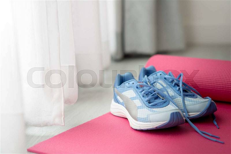 Blue sport shoes on pink yoga mat with nature light in the morning, stock photo