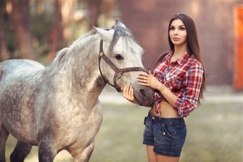 Portrait of young cowgirl and white horse outdoors, stock photo
