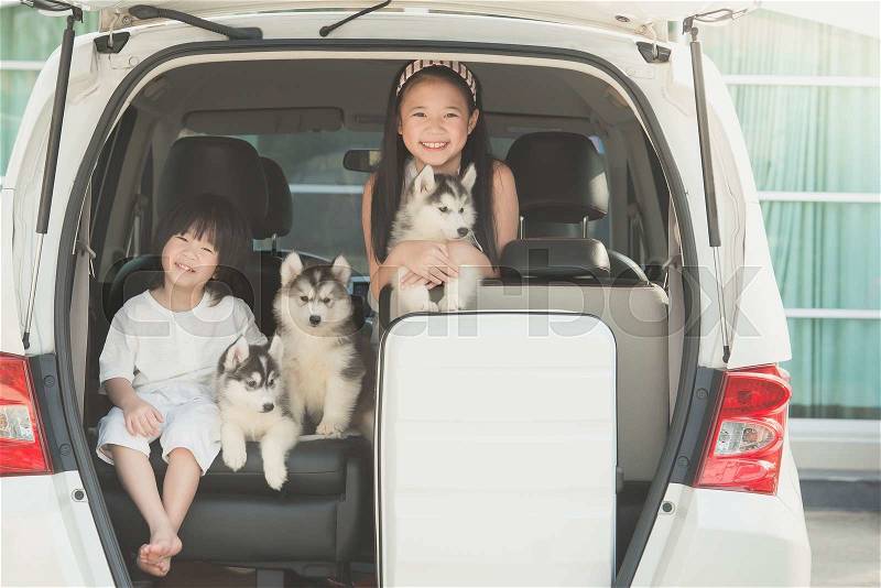 Happy asian children and siberian husky puppies sitting in the car, stock photo