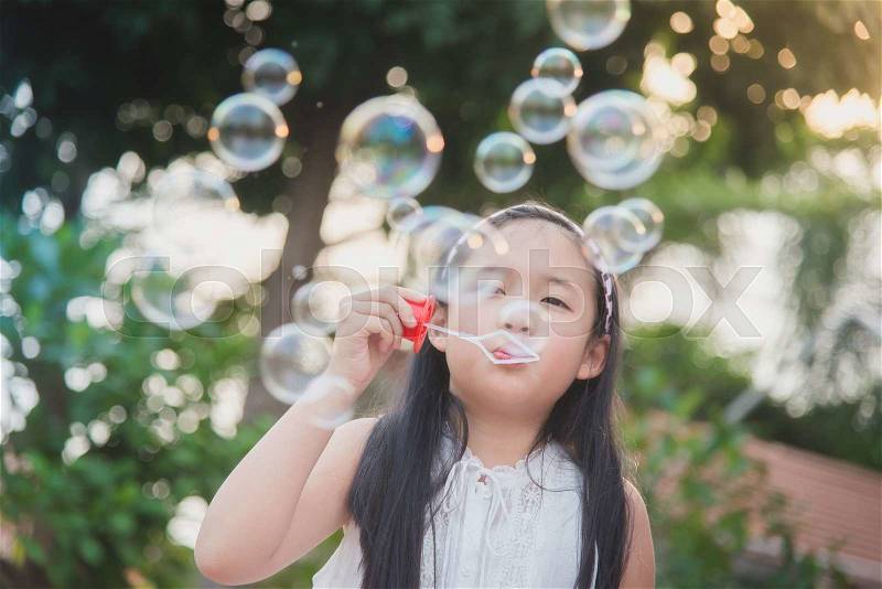Cute asian girl is blowing a soap bubbles,vintage filter, stock photo