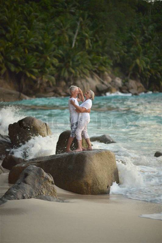 Beautiful happy elderly couple dancing at tropical resort, stock photo