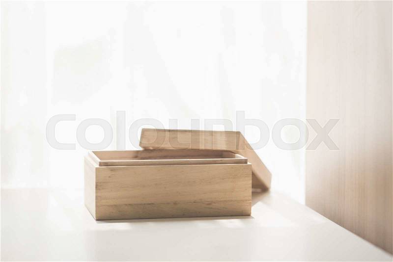 Open wooden box on white table under sunlight, stock photo