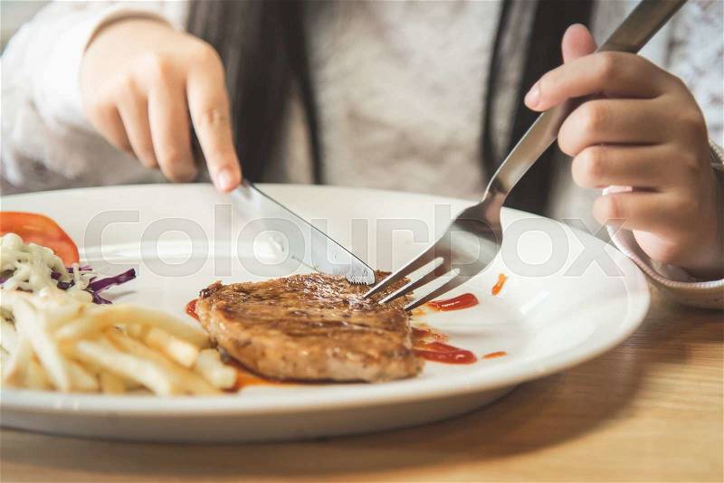 Asian girl eating pork steak with Vegetables on white disk, stock photo