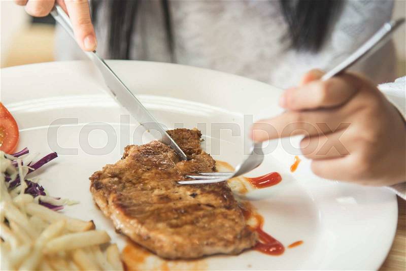 Asian girl eating pork steak with Vegetables on white disk, stock photo