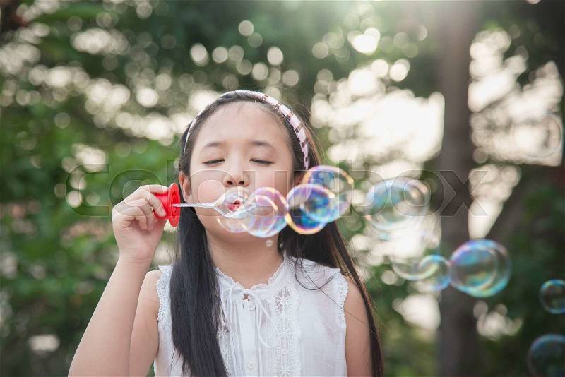 Cute asian girl is blowing a soap bubbles,vintage filter, stock photo