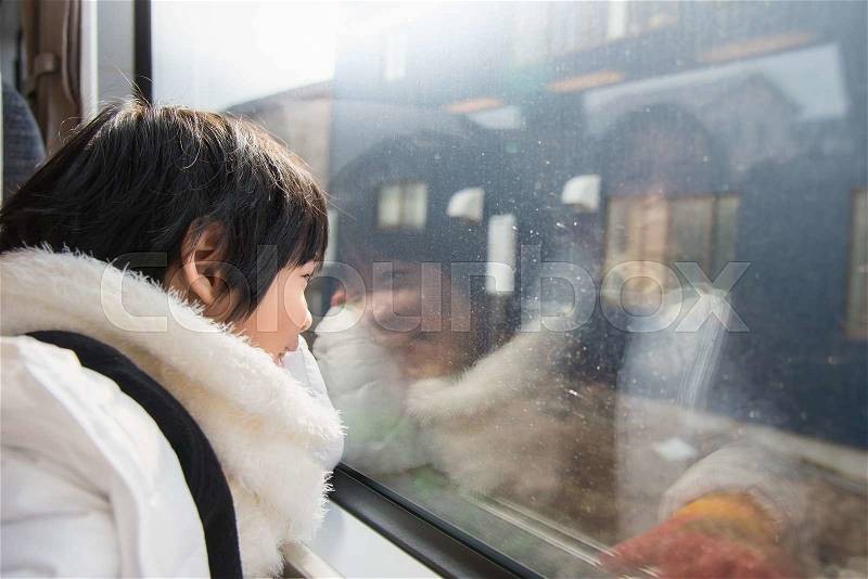 Happy asian child looking out train window outside, while it moving. travel, stock photo