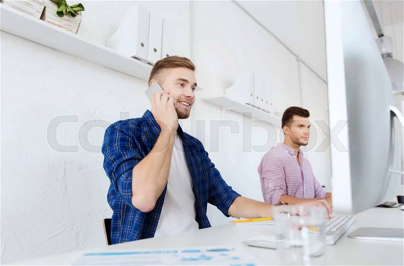 Business, technology, education and people concept - happy young creative man or student with computer at office calling on smartphone, stock photo
