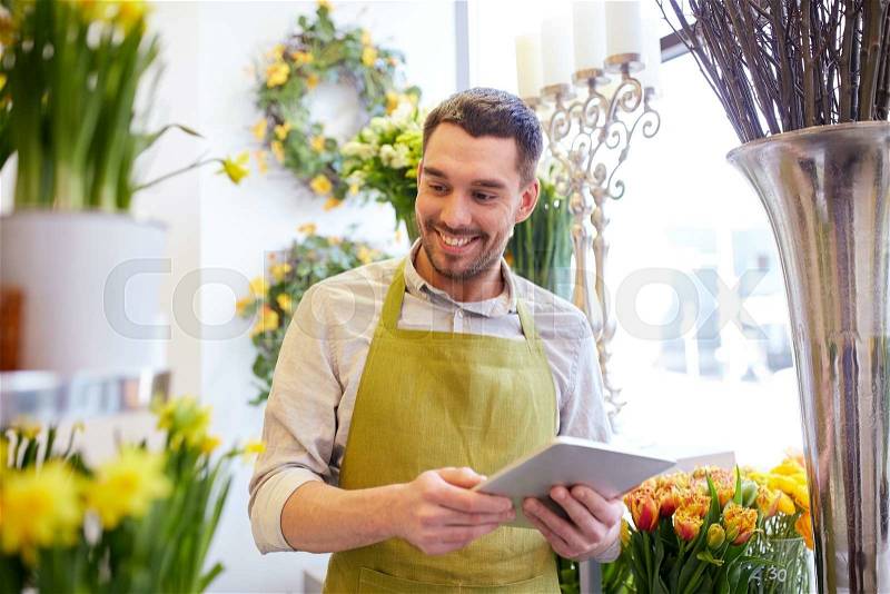 People, business, technology, sale and floristry and concept - happy smiling florist man with tablet pc computer at flower shop, stock photo