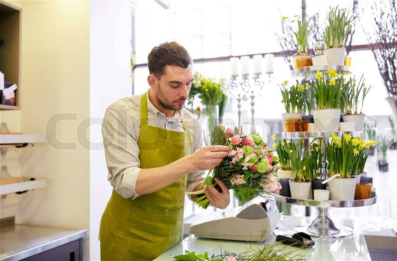 People, business, sale and floristry concept - florist man making bunch at flower shop, stock photo