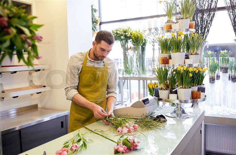 People, business, sale and floristry concept - florist man making bunch at flower shop, stock photo