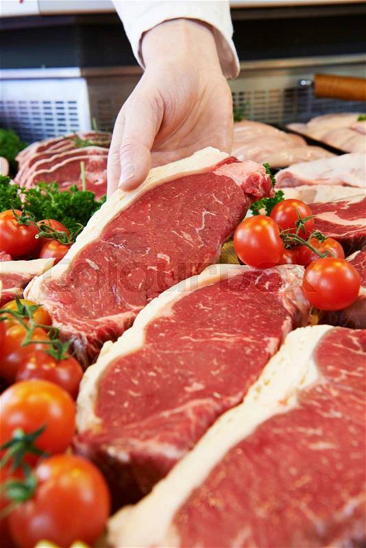 Butcher Showing Customer Sirloin Steak In Refrigerated Display, stock photo